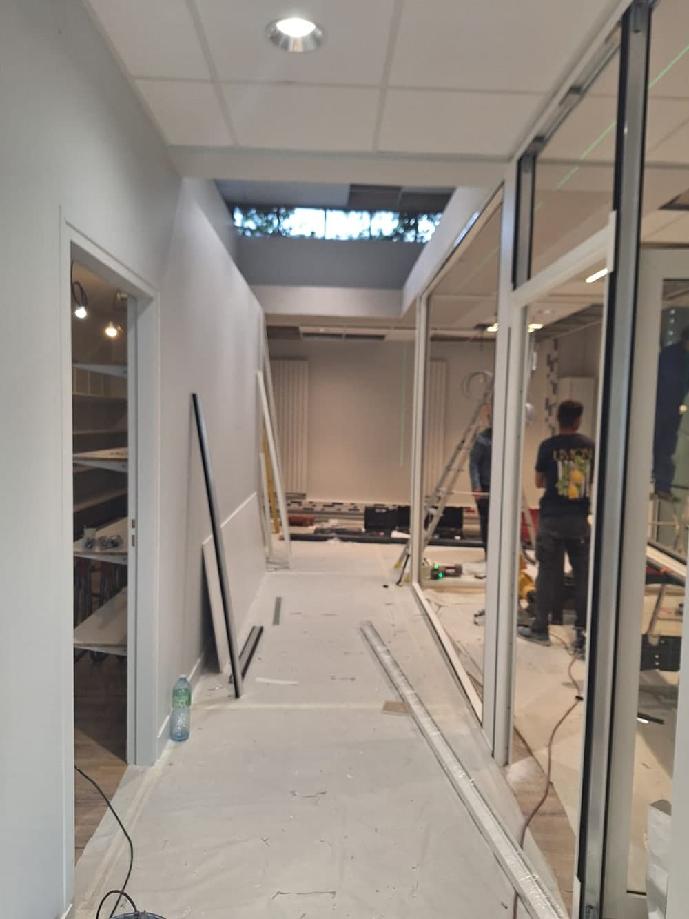 Couloir vitré en fin de chantier, protections au sol et vitrages en cours de pose