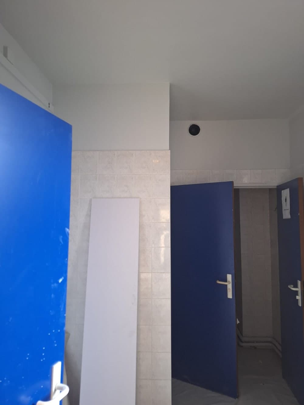 Sanitaires neufs en fin de chantier, panneau posé contre le mur